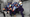 On Wall Street, a group of men in wolf masks and business suits hold stacks of money.